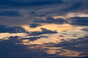 Sunset sky with golden rays of the sun against the background of silhouettes of mountain landscapes and rural villages