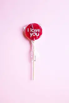 Feeling Prints: a sweet wrapped 'I Love you' red lollypop against a pastel yellow background