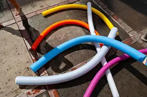 Hawaii Prints: Swimming noodles used as floatation devices on the ground near the swimming pool