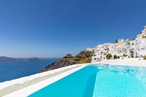 Swimming poolside, infinity pool relaxation view out over the sea caldera of Santorini Greece. Luxury travel, summer holiday vacation, peaceful resort