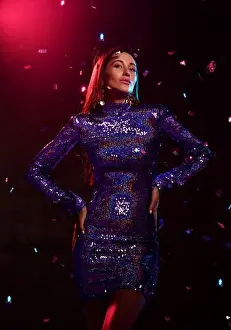 Glance Prints: Tall sexy brunette woman in glittering tight mini dress and stylish accessories stands under confetti fall