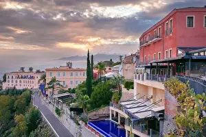 Taormina, Sicily, Italy. Cityscape image of picturesque town of Taormina, Sicily with volcano Mt. Etna in the background at sunset