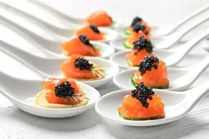 Dainty Prints: Tasty appetizers with black caviar and salmon in ceramic spoons on table