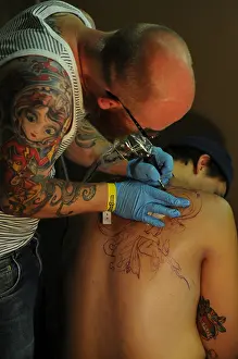 Bald Prints: Tattooist working on a back piece during a tattoo convention