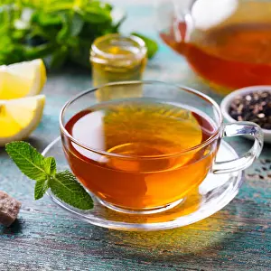 Darjeeling Prints: Tea cup with mint leaf and lemon. Wooden background. Close up