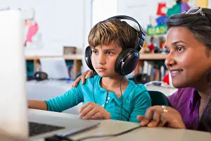 Encouraging Prints: Teacher helping student using laptop