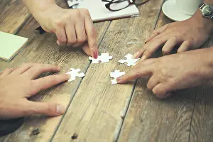 Team work concept, Hands hold puzzles on wood table