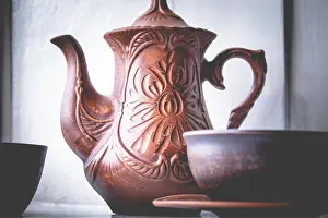 Boiled Prints: A teapot and a cup of clay are standing near the window. Close-up