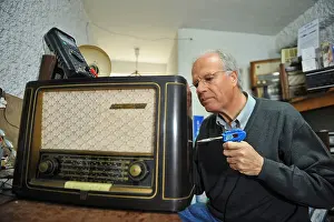 Middle Aged Prints: Technician repairing an old 1950's Grundig 941W radio in his workshop