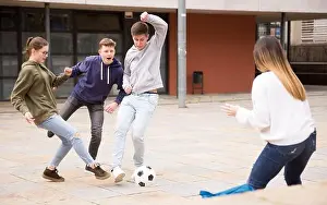 Catching Prints: Teen friends spending time together outdoors playing with ball on square near school