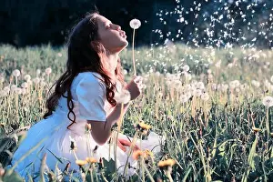 Freedom Summer Prints: Teen girl blowing seeds from a flower dandelion in spring park