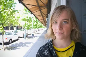 Grinning Prints: Teen sitting under a storefront awning looking at camera