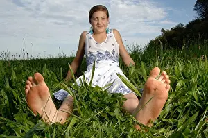 Barefooted Prints: Teenage girl wearing a dress sitting with bare feet in the grass