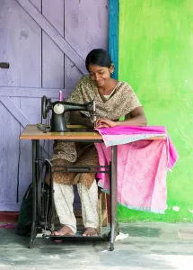 Ethnic Prints: Teenage Indian girl on a sewing machine making clothes in a rural indian village