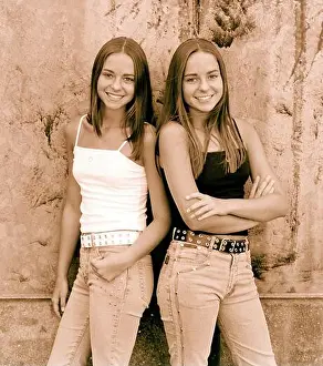 Sisters Prints: Teenage twin girls standing by wall outdoors