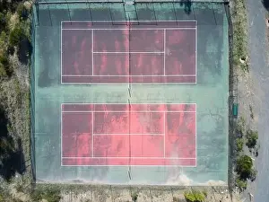 Background Texture Prints: Empty tennis court aerial view showing a red surface court with green edges and white marking lines
