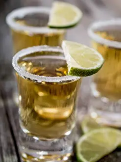 Tequila Prints: Tequila shots served with salt rim and lime wedges on a grunge wooden table