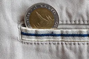 Thai coin with a denomination of 10 baht in the pocket of beige denim jeans with blue stripe