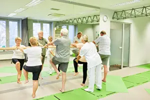 Senior Citizen Prints: Therapist cares for seniors in physiotherapy on the ballet bar as a fall prevention