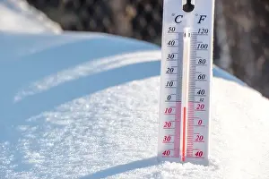 Thermometer Prints: The thermometer lies on the snow and shows a negative temperature in cold weather on the blue sky