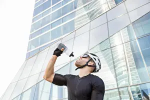 Financial District Prints: Thirsty cyclist drinking water from bottle in front of office building