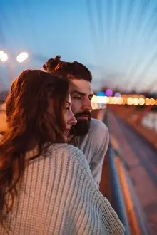 Mid Adults Prints: Thoughtful couple looking away while standing on bridge in city at dusk