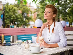 Dreaming Prints: Thoughtful young woman in a sidewalk cafe with a cup of latte