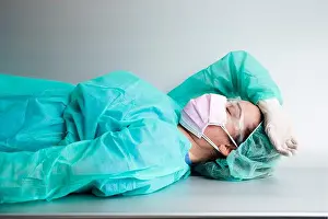 45 50 Years Prints: Tired female doctor wearing protective workwear resting on bench in hospital
