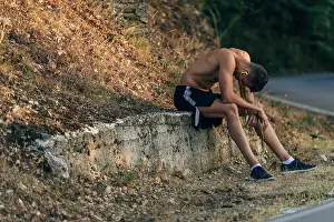Exhausted Prints: Tired male runner sweating and breathing after running hard in countryside road