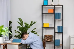 Exhausted Prints: A Tired Person Sitting at Their Desk in a Modern Workspace