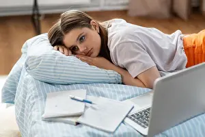 Depressed Prints: tired student girl with laptop lies on bed at home