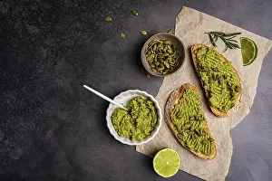 Starter Prints: Toast with fresh avocado, herbs and seeds with lemon slices on dark background