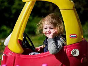 2 3 Years Prints: Toddler driving a Little Tikes Cozy Coupe toy car around the garden, UK