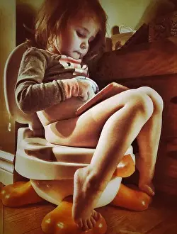 Toilet Prints: Toddler girl sitting on potty while playing with a tablet