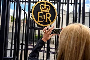 Elizabeth Prints: Tourist in London taking close up photos of the Buckingham Palace ER sign, United Kingdom