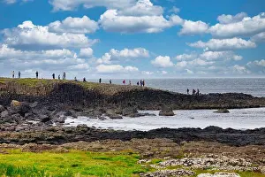 Basalt Prints: Tourists climbing on the ancient basalt colums of the Giant's Causeway UNESCO World Heritage Site