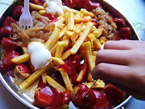 Mayonnaise Prints: A traditional Berlin dish of french Fries with curry sausage and sautéed onions with a child‘s hand reaching for a fry