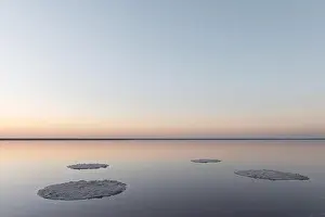 Tranquil minimalist landscape with smooth surface of the pink salt lake with calm water with horizon with clear sky in sunrise time