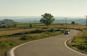 Craggy Prints: Transportation background. Car going on curvy village road