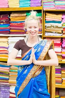 Saree Prints: Travel photo of beautiful blond Caucasian tourist woman trying to wear a traditional Indian saree in local saree shop