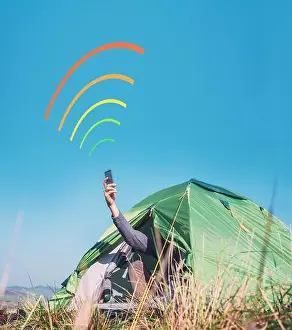 Texting Prints: Traveler siting in touristic tent rising the hand with smartphone out and trying to catch cellular network signal