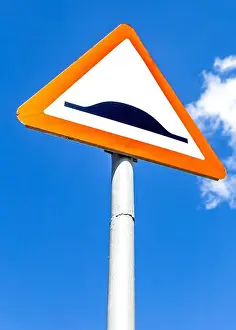 Uneven Prints: Triangle speed bump road sign against the blue sky. Warning traffic sign Speed bump