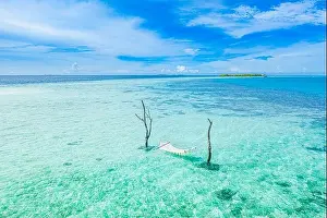 Sunset Landscape Prints: Tropical island coast as summer landscape with swing or hammock and amazing calm sea lagoon for beach banner