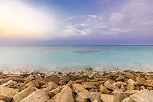 Afterglow Prints: Tropical island view with beautiful sunset over the green boulders on a wave breaker