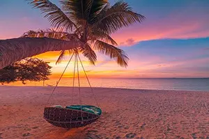 Tropical sunset beach background as summer coast landscape panorama with leisure beach swing on palm, white sand and calm sea beach horizon