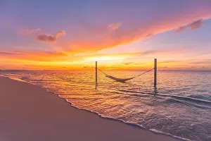 Tropical sunset beach background as summer landscape panorama with beach swing hammock and white sand and calm sea beach banner. Perfect beach scene