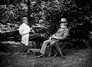 Communicating Prints: TURN OF THE CENTURY TWO MEN SITTING OUTSIDE IN CHAIRS AMONG TREES SMOKING CIGARS TALKING DOG LAYING AT THEIR FEET
