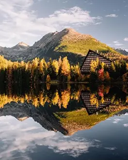 Turquoise frozen water of Lake Carezza (Karersee) in Western Dolomites, Italy. Beautiful close up view with stones and pines reflection
