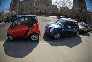A two-seat Smart car, left, manufactured by Daimler and a Mini Cooper are seen squeezed into a parking spot in New York