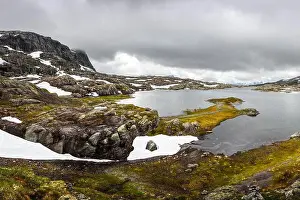 Typical norwegian landscape with snowy mountains and clear lake near the Trolltunga rock - most spectacular and famous scenic cliff in Norway
